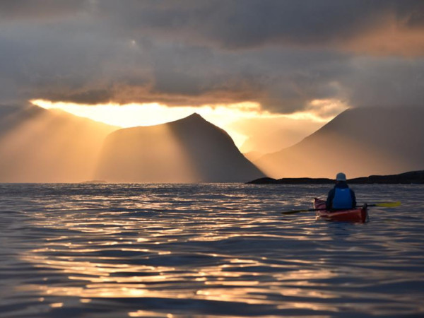 A kayak padler looking at the sun breaking through clouds at sea. Photo